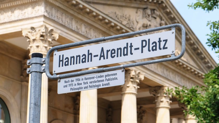 Bild: © Focke Strangmann Foto eines Straßenschildes mit der Aufschrift "Hannah-Arendt-Platz" mit dem Portikus des Niedersächsischen Landtages im Hintergrund