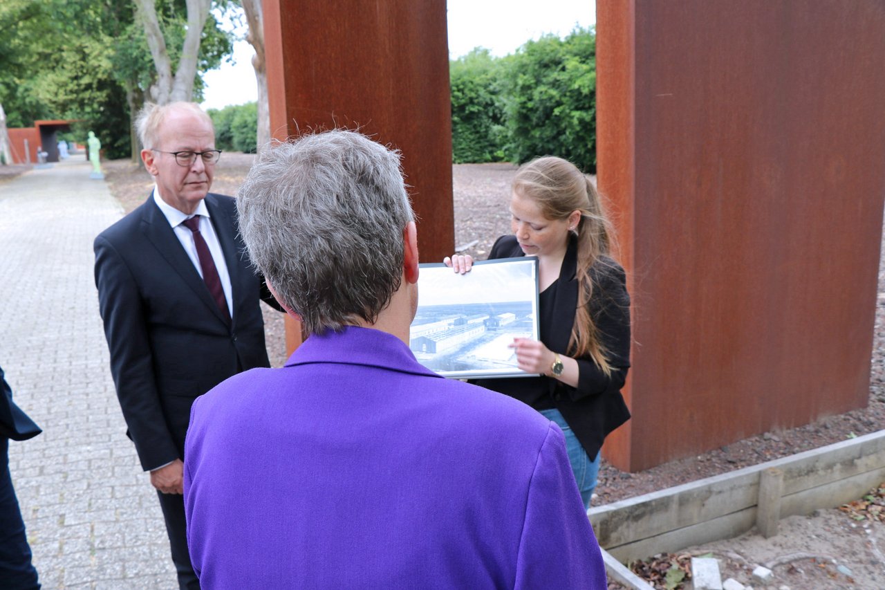 Landtagspräsidentin Naber von hinten, eine Vertreterin der Gedenkstätte Esterwegen zeigt ein Bild.