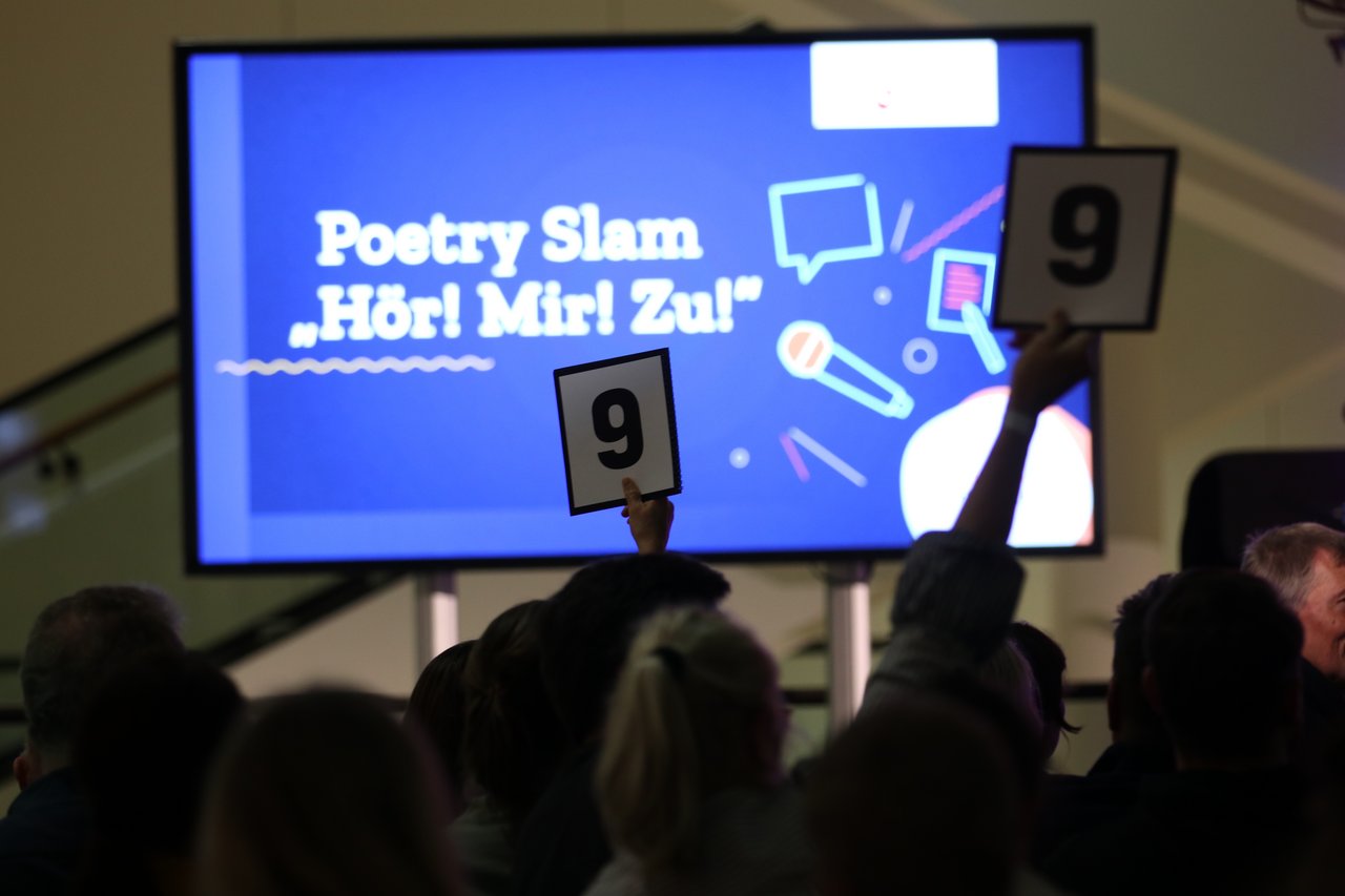 Monitor mit dem Schriftzug "Poetry Slam - Hör mir zu".