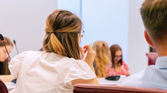 Bild: © Niedersächsischer Landtag Mehrere junge Menschen sitzen an einem Konferenztisch. Im Fokus eine junge Frau mit einem Kugelschreiber in der Hand, die aufmerksam zuzuhören scheint.