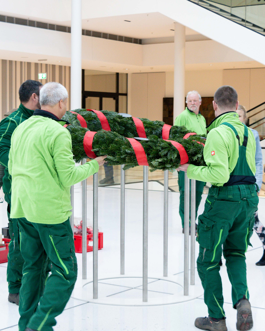 Mitarbeitende der Evangelischen Stiftung Neuerkerode stellen den Adventskranz in der Portikushalle auf.